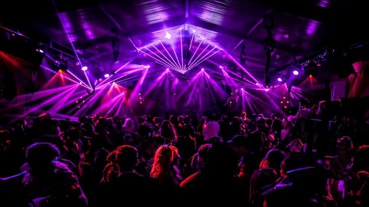 Crowd under purple laser lights at a live show